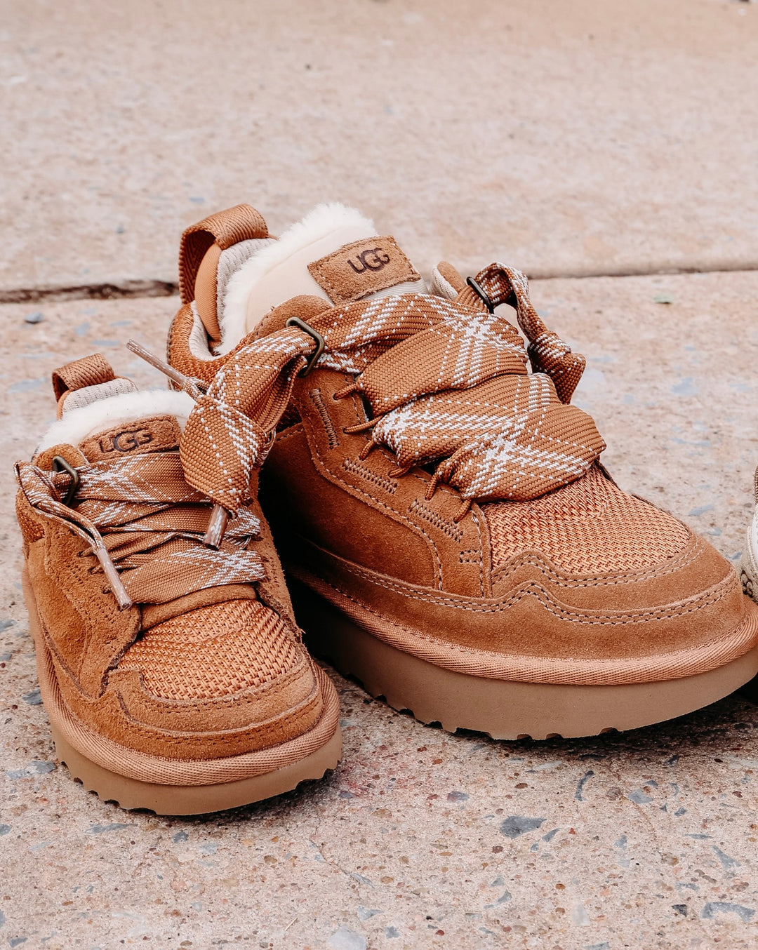 2 chestnut sheepskin suede sneakers with brown plaid laces and fur with UGG logo