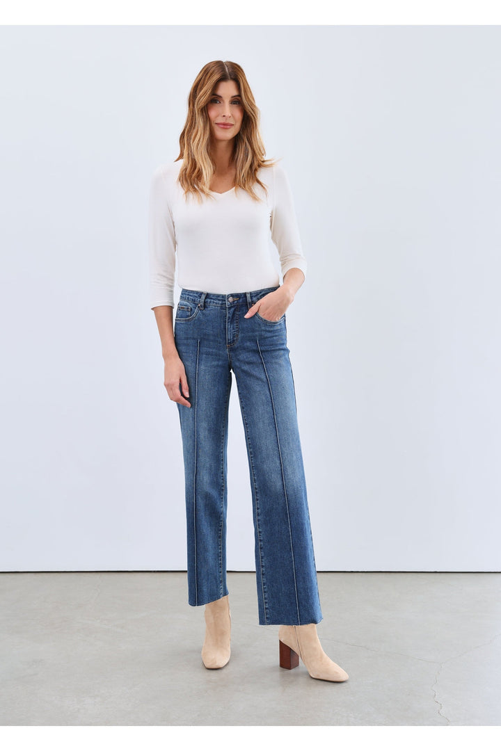 Woman wearing cream 3/4 sleeve V-neck top with wide-leg blue jeans and beige booties