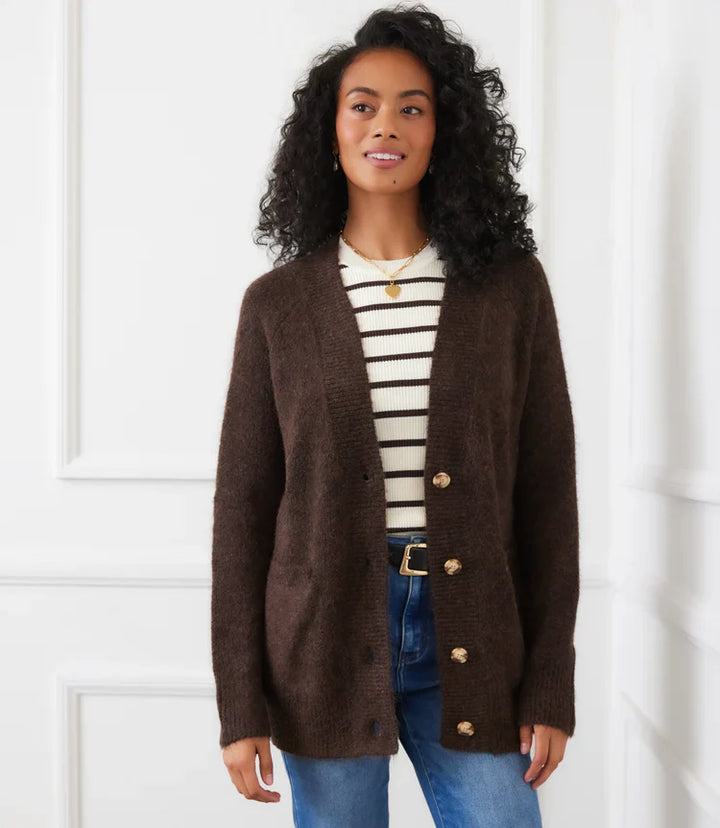Woman wearing dark brown button-up cardigan sweater over striped top with jeans