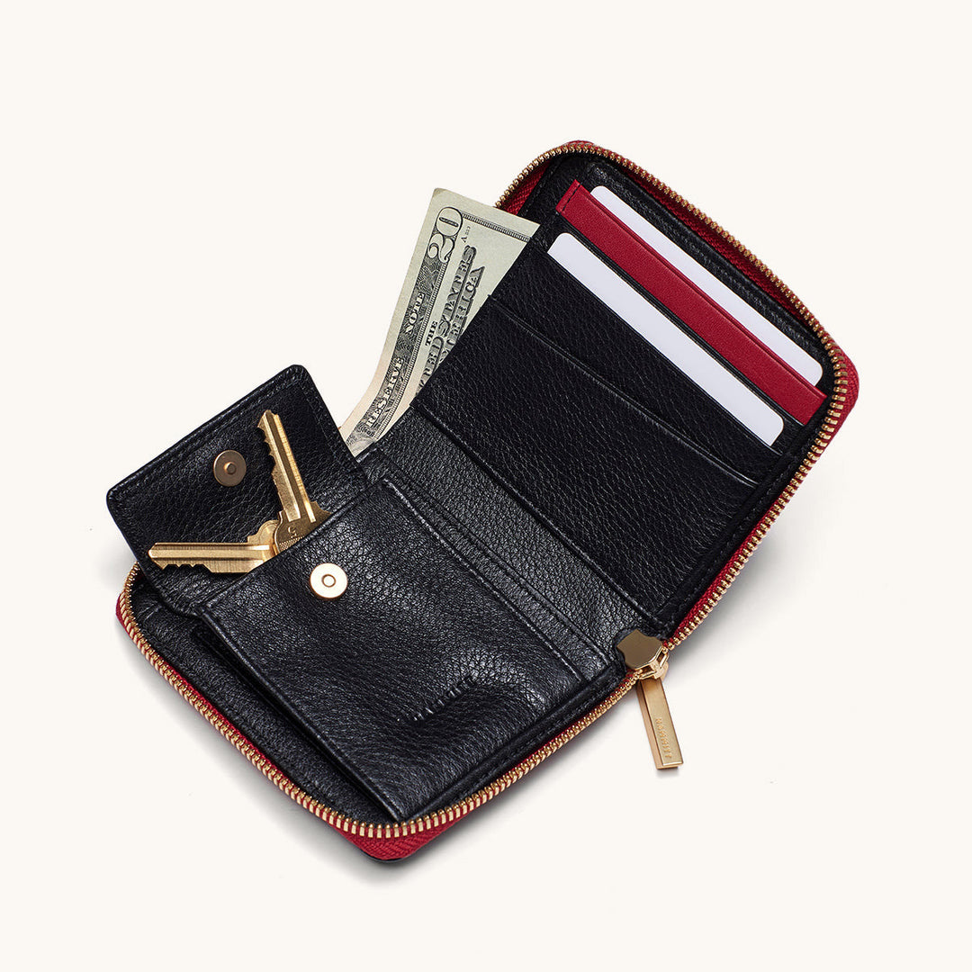Hammitt 5 North wallet open showing black interior, red zip, gold hardware, cards, cash, and key