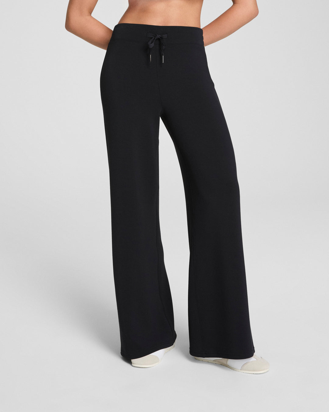 Woman wearing black wide leg pants with drawstring waist on neutral background