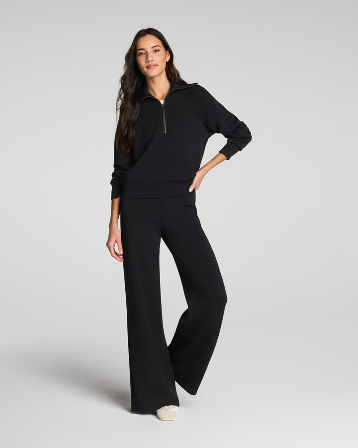 Woman wearing black wide leg pants and matching hoodie in studio portrait