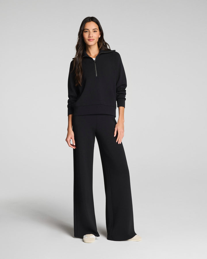 Woman wearing black wide leg pants and matching hoodie in studio photo