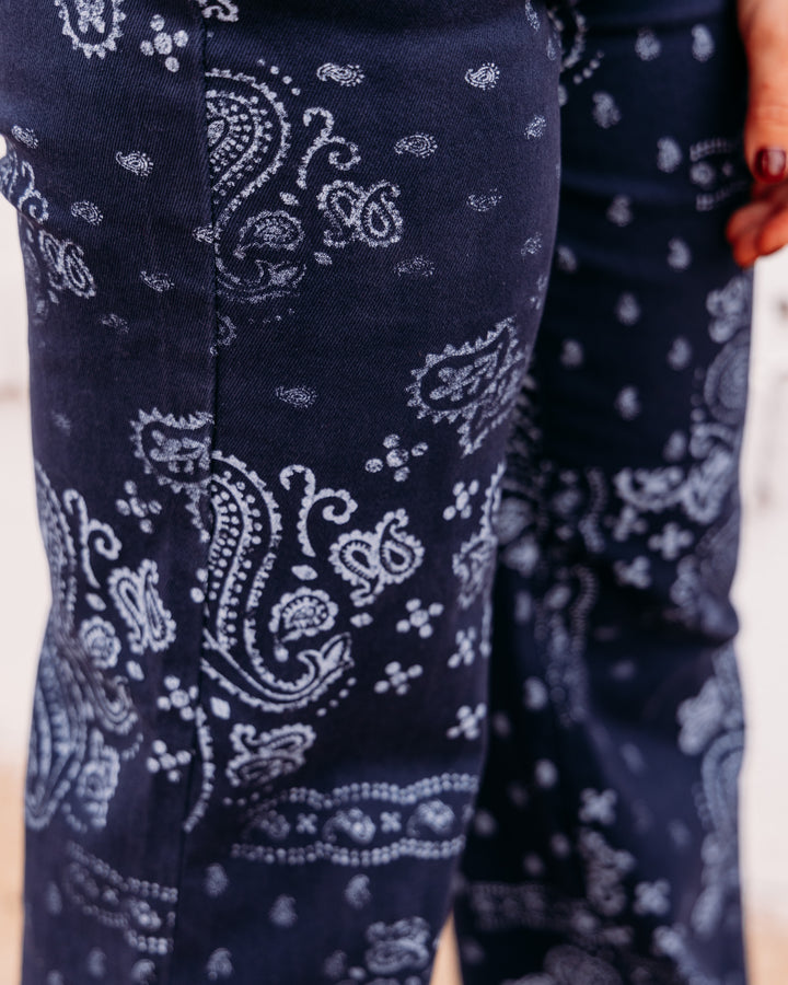 Close-up of dark navy pants with a white paisley bandana print, worn by a model.