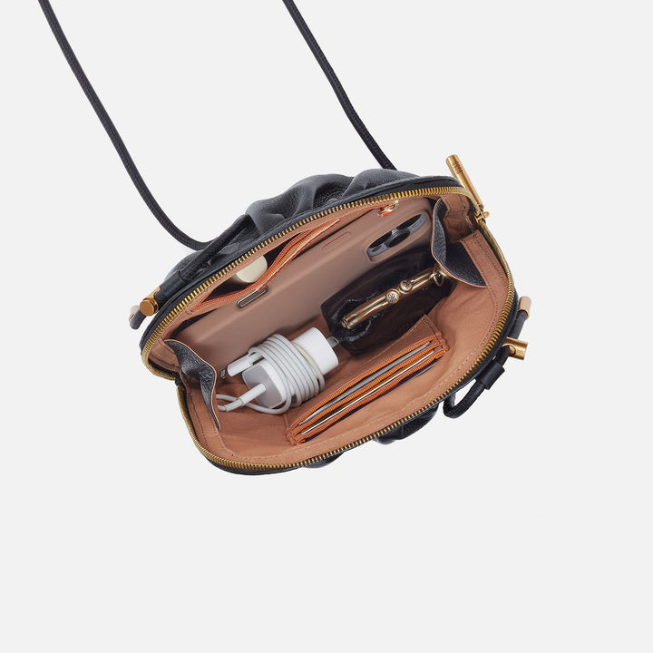 Open black leather crossbody bag showing interior compartments with phone and charging cable