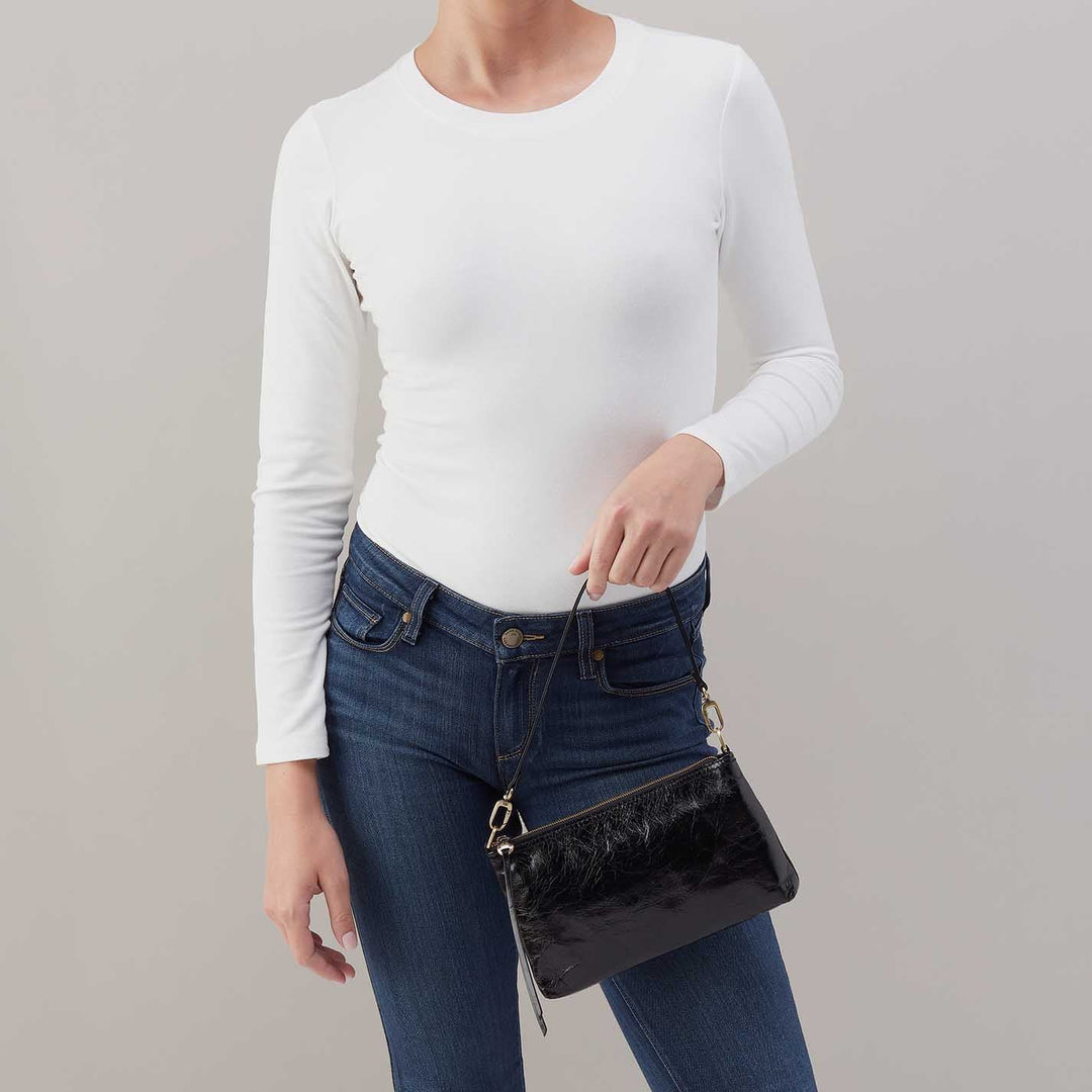 Woman wearing white long-sleeve shirt and jeans carrying black leather crossbody bag