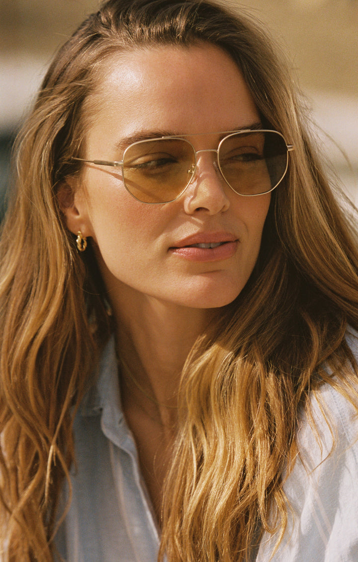 Woman wearing Z Supply Highway Satin Gold sunglasses with brown polarized lenses outdoors