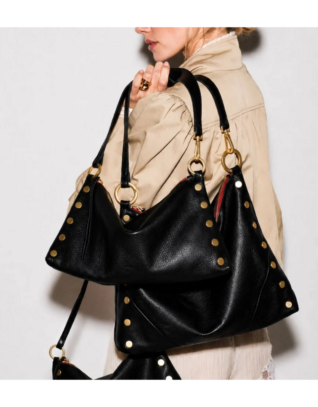 Model carrying large black leather Hammitt Kyle bag with gold studs and hardware