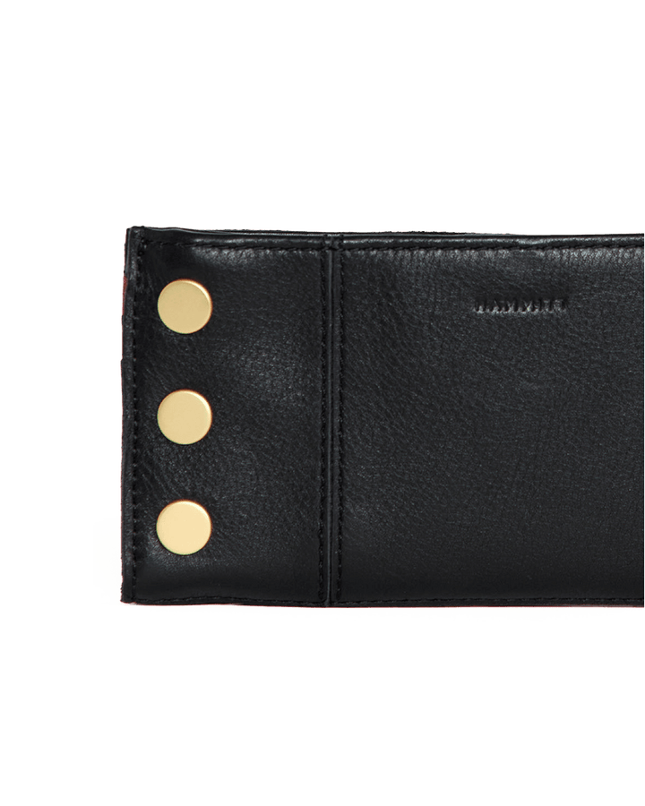 Hammitt 110 North wallet detail shot showing black leather with gold studs and red zip